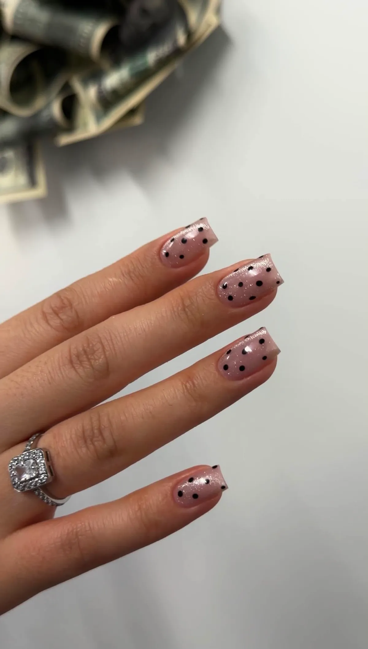 Sheer pink shimmer nails with hand-painted black polka dots